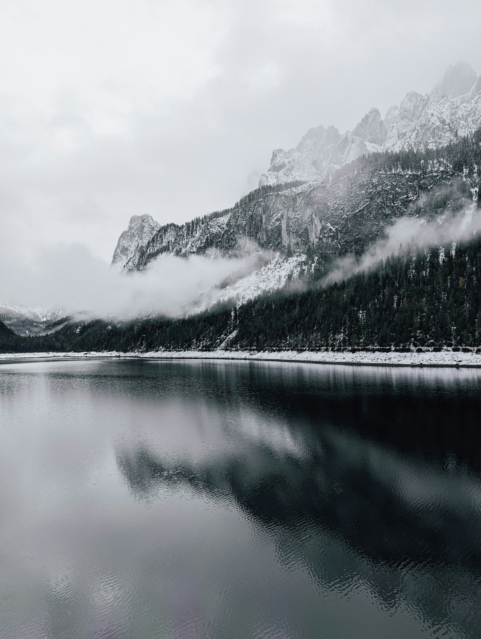 A quiet mountain lake surrounded by green forest and mist